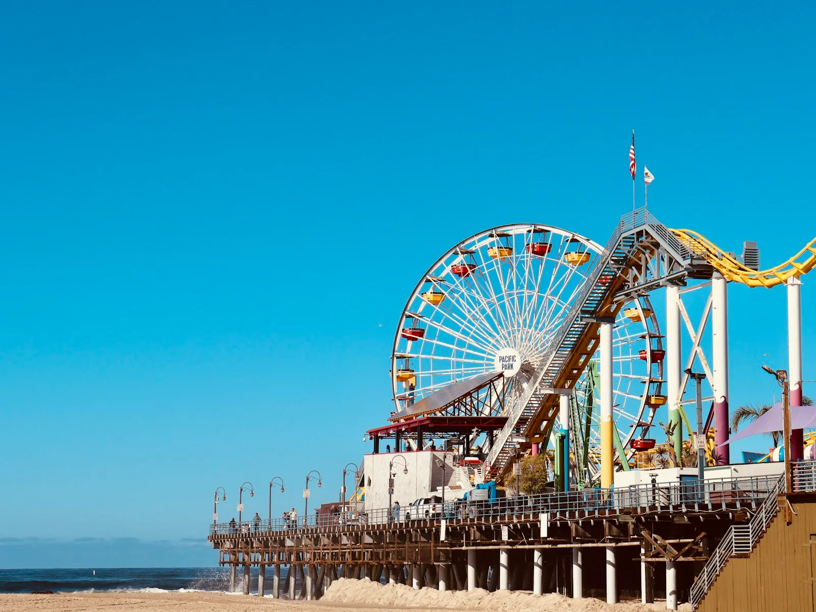 Roda-gigante e montanha-russa do píer de Santa Monica sob céu azul